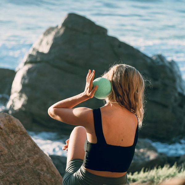 Two women sitting back to back in a meditative yoga pose in nature.